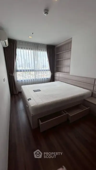 Modern bedroom with large window and built-in storage in a stylish apartment.
