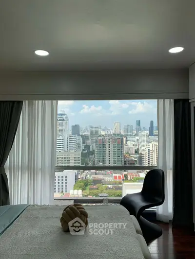 Luxurious bedroom with stunning city view through large windows, featuring modern decor and cozy ambiance.