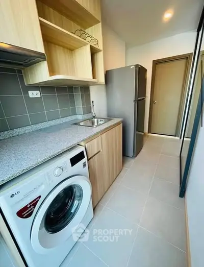 Modern kitchen with washing machine and fridge in compact layout