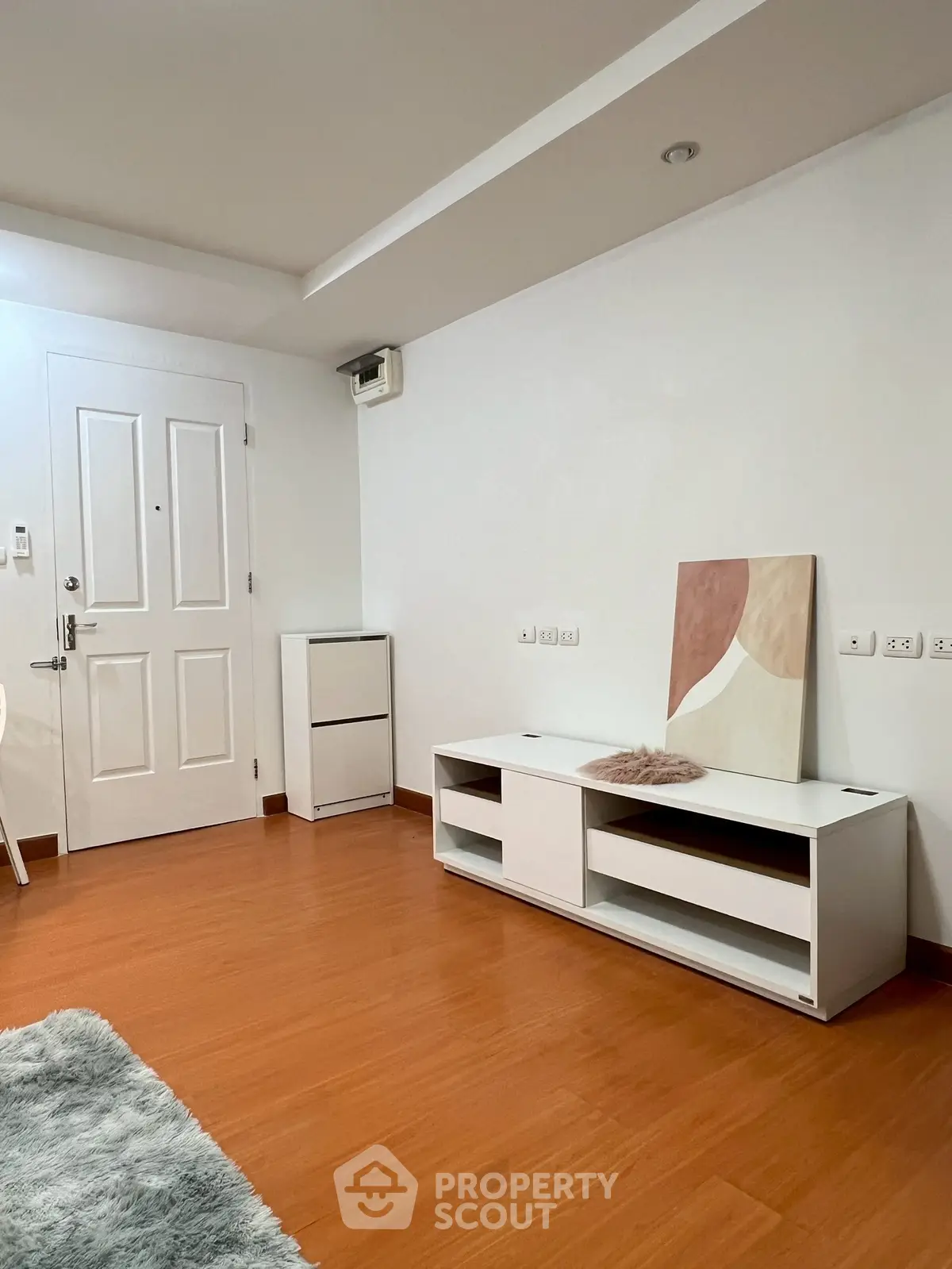 Minimalist interior with wooden flooring and white furniture in a cozy living space.