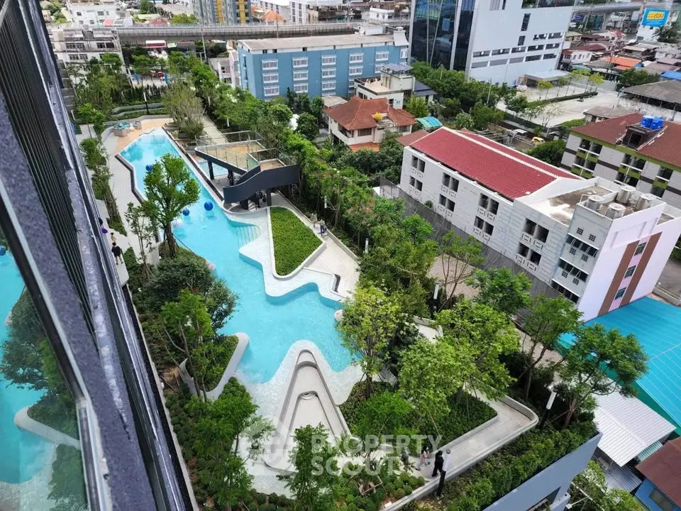 Stunning aerial view of modern residential complex with lush gardens and unique pool design.