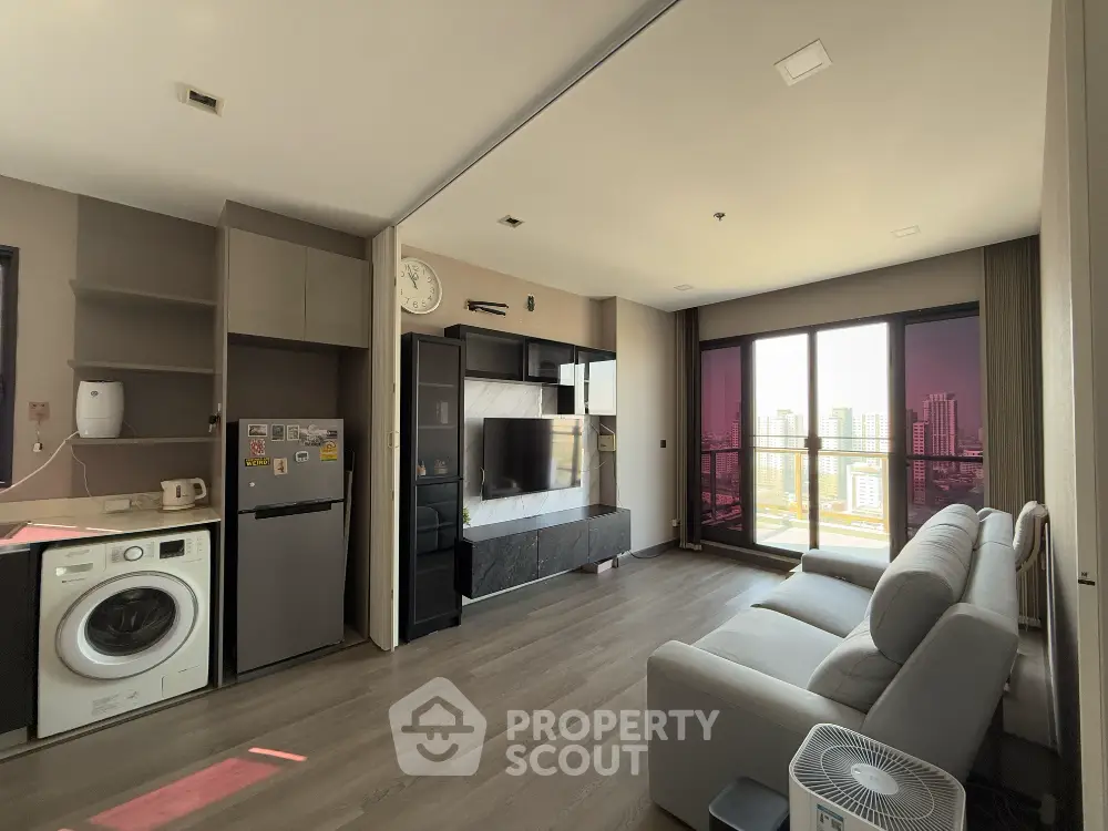 Modern living room with city view, featuring washing machine and sleek furniture.