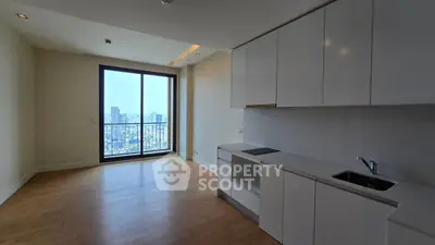 Spacious modern kitchen with city view, sleek white cabinets, and hardwood floors.
