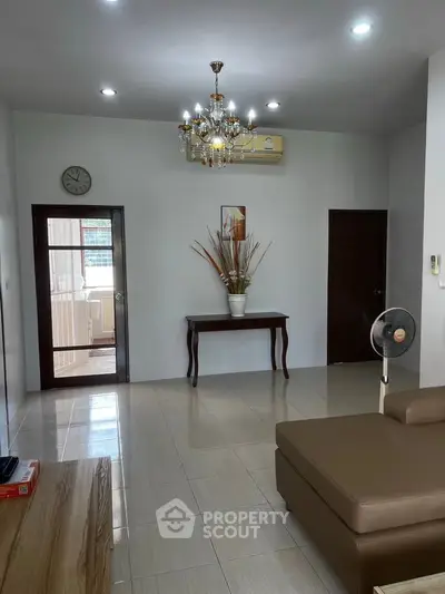 Spacious living room with elegant chandelier and modern furniture in a cozy apartment.