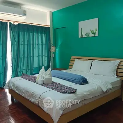 Cozy bedroom with teal accents and modern decor, featuring a comfortable bed and natural light.