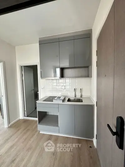 Modern compact kitchen with sleek cabinetry and wood flooring in a contemporary apartment.