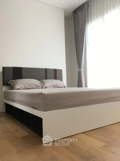 Modern bedroom with sleek design and natural light, featuring a stylish bed and elegant curtains.