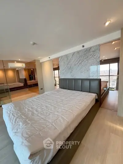 Luxurious modern bedroom with panoramic city view and elegant marble accent wall.