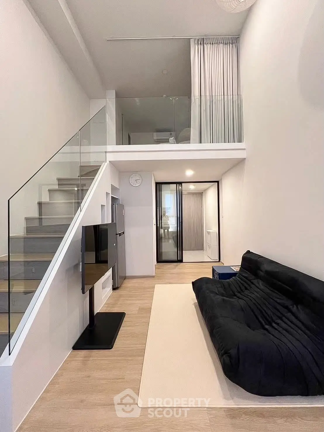 Modern loft-style living room with sleek staircase and cozy sofa