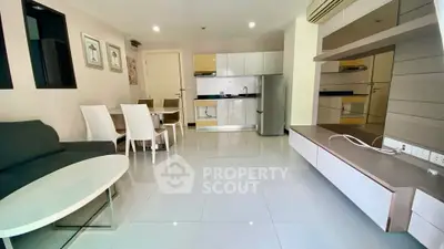Modern open-plan living room with sleek kitchen and dining area, featuring glossy tiles and contemporary furniture.