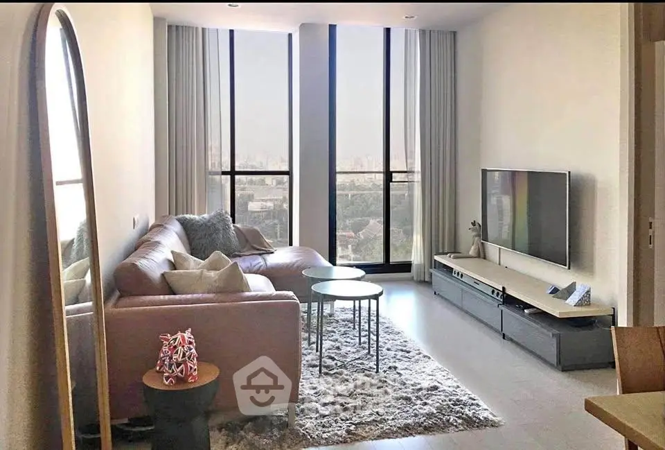 Modern living room with large windows and city view, featuring a cozy sofa and sleek TV setup.