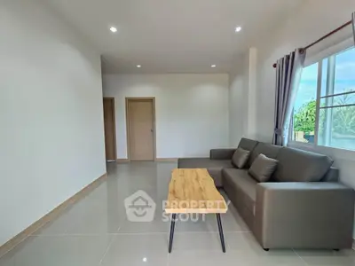 Modern living room with sleek sofa and wooden coffee table, bright natural light through large window.