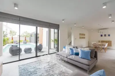 Spacious modern living room with pool view, stylish decor, and open dining area, perfect for luxury living.