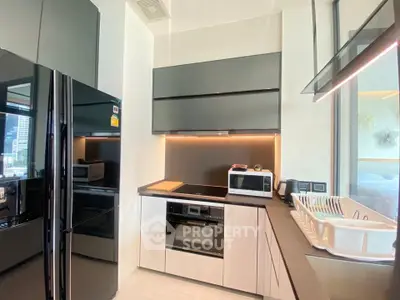 Modern kitchen with sleek black appliances and open layout in a high-rise apartment.
