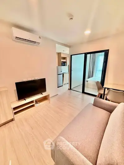 Modern living room with sleek furniture and open layout, featuring a cozy sofa and flat-screen TV.