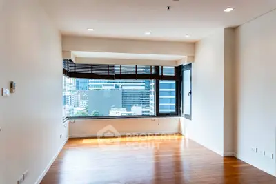 Spacious modern living room with large window offering city views and wooden flooring.