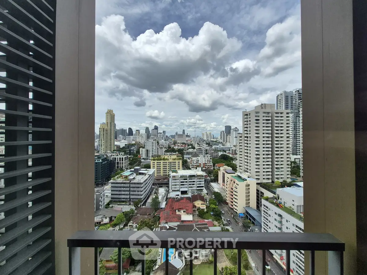 Stunning cityscape view from a high-rise balcony with urban skyline and cloudy sky.