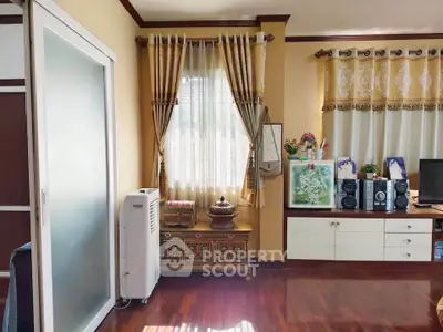 Charming living room with elegant curtains and wooden flooring, featuring a stylish cabinet and modern decor.