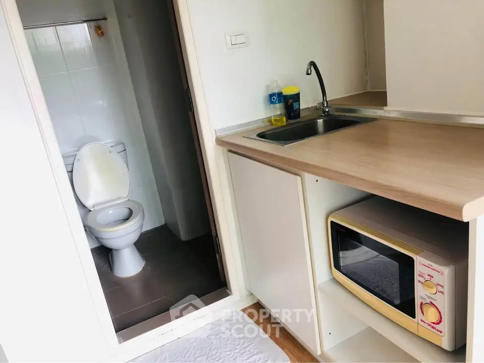 Compact kitchenette with adjacent bathroom in a cozy apartment setting.