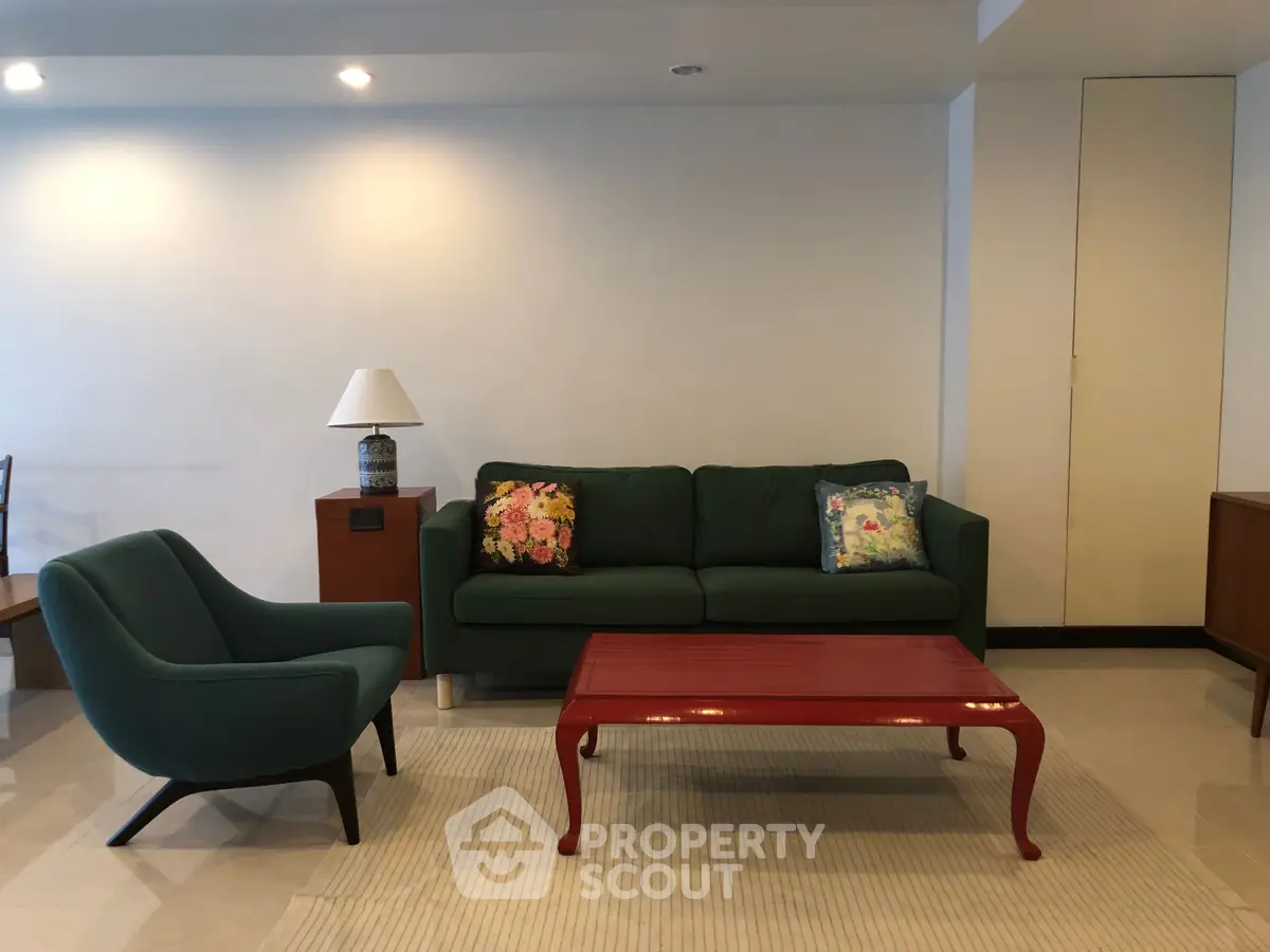 Elegant living room with stylish green sofa, armchair, and vibrant red coffee table.