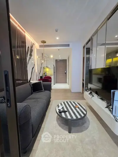 Modern living room with stylish decor, featuring a sleek sofa, contemporary lighting, and a flat-screen TV.