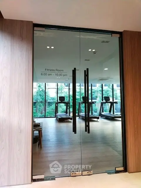 Modern fitness room with glass doors and treadmills in a luxury building.
