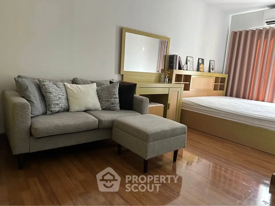 Cozy bedroom with stylish sofa and wooden furniture, perfect for modern living.