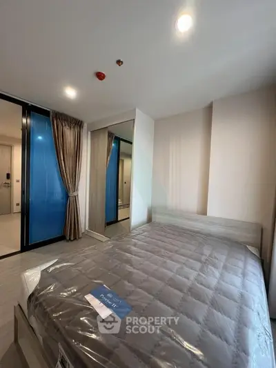 Modern bedroom with sleek design and mirrored wardrobe in a stylish apartment.