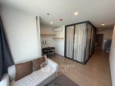 Modern living room with glass partition and cozy seating area in a stylish apartment.