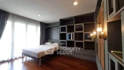 Spacious bedroom with modern built-in shelving and large windows for natural light.