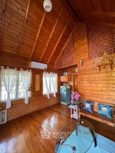 Charming wooden interior with high ceilings and cozy decor, featuring a vintage fridge and natural light.
