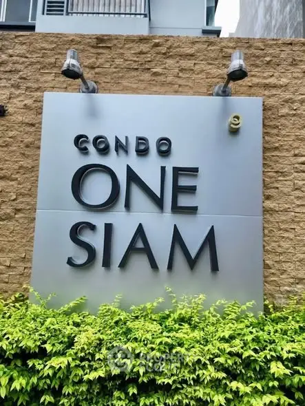 Condo One Siam exterior signage with lush greenery