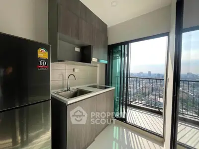 Modern kitchen with sleek cabinetry and city view from balcony in high-rise apartment.