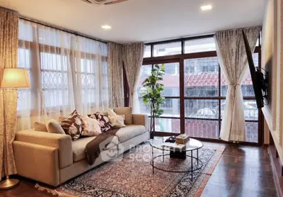 Spacious living room with large windows, cozy sofa, and elegant decor in a modern apartment.
