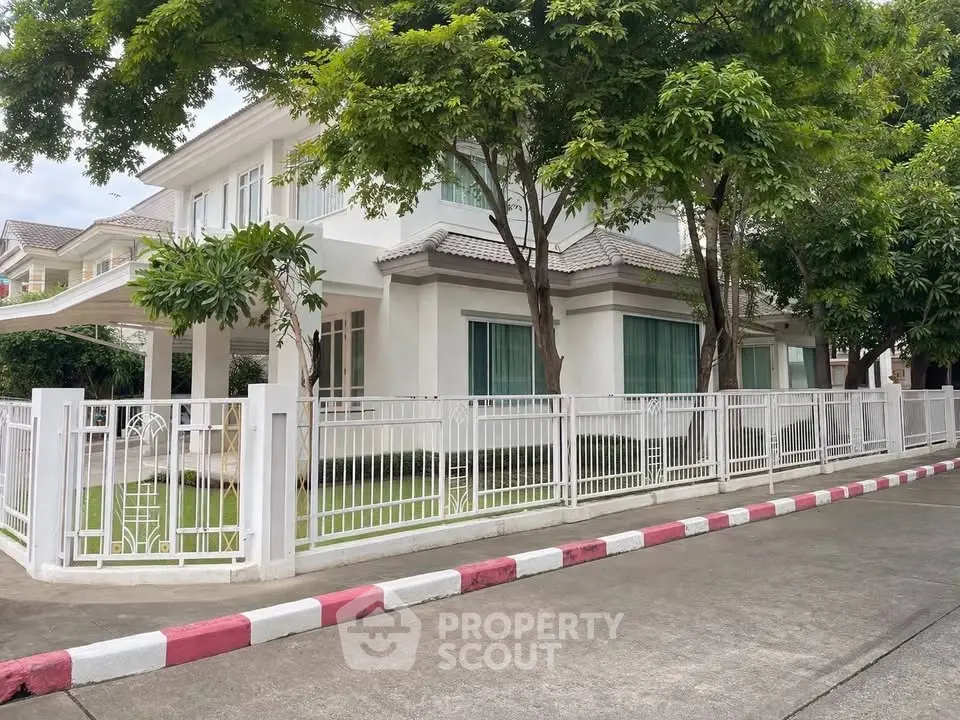 Charming suburban house with lush greenery and white picket fence, perfect for family living.
