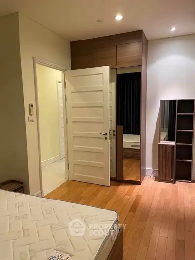 Spacious bedroom with wooden flooring and built-in wardrobe, perfect for modern living.