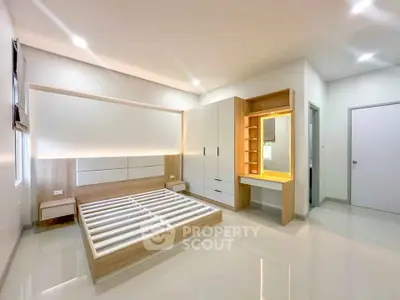Spacious modern bedroom with sleek built-in wardrobe and illuminated vanity area.