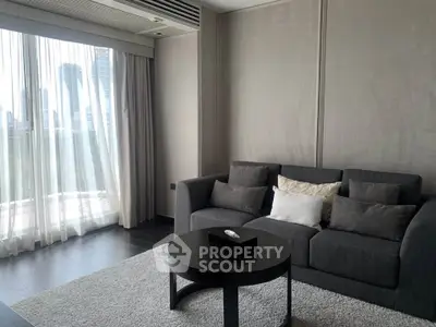 Modern living room with city view, featuring a sleek gray sofa and elegant decor.