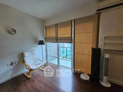 Cozy living room with modern decor and balcony view, featuring wooden flooring and stylish blinds.