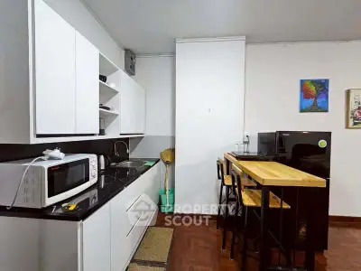 Modern kitchen with sleek black and white design, featuring a microwave and breakfast bar.