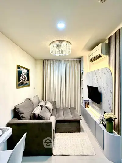 Modern living room with elegant chandelier and cozy gray sofa, perfect for relaxation and entertainment.