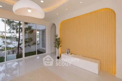 Modern living room with elegant lighting and large windows overlooking a serene garden view.