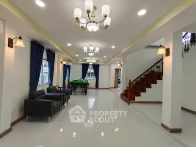 Spacious living room with elegant lighting and pool table, perfect for entertainment.
