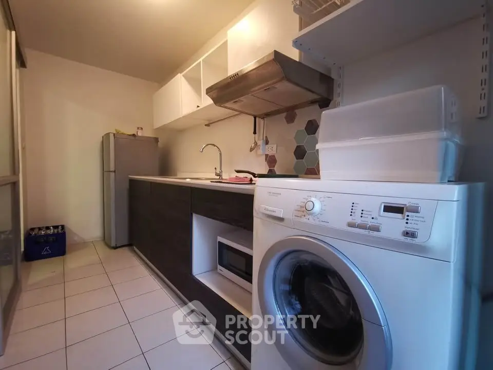 Modern kitchen with washing machine and sleek cabinetry in a cozy apartment.