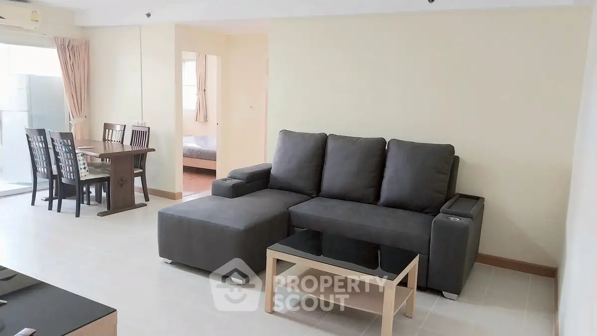 Spacious living room with modern furniture and dining area in open layout apartment.