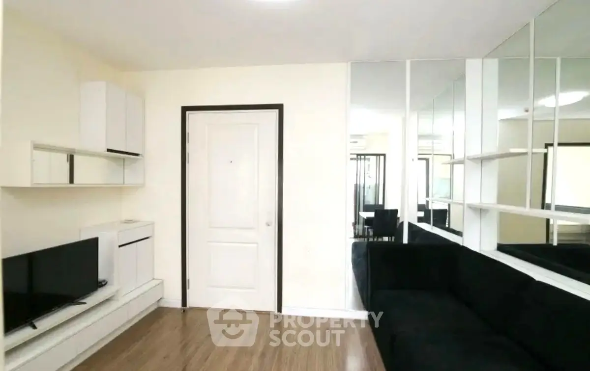 Modern living room with sleek black sofa and mirrored wall accents