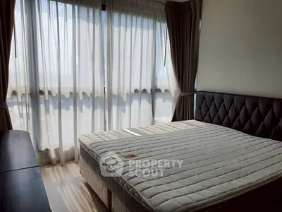 Bright bedroom with large windows and elegant curtains, featuring a comfortable bed and stylish headboard.