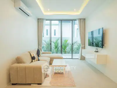 Modern living room with sleek design, featuring a large sofa, wall-mounted TV, and floor-to-ceiling windows.