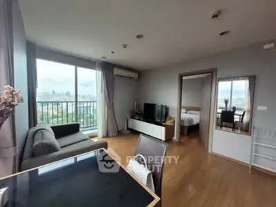 Modern living room with city view, featuring sleek furniture and large windows.
