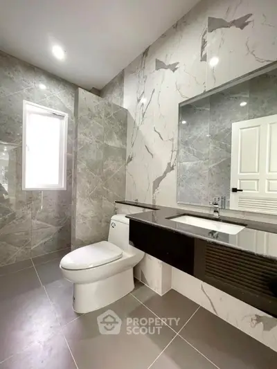 Luxurious modern bathroom with marble walls and sleek fixtures.
